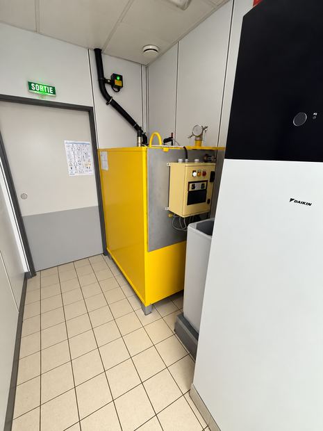 Cuve jaune en place dans un local technique propre, avec coffret de commande et raccordements.
