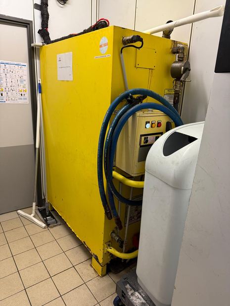 Cuve jaune encrassée : dépôts et coulures sur les parois, tuyauteries et flexibles laissés en place.